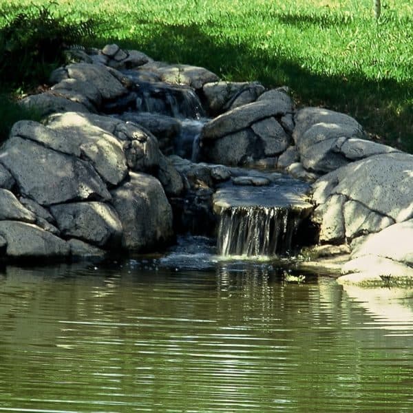 A small artificial waterfall that falls into a pond in Aledo Texas.