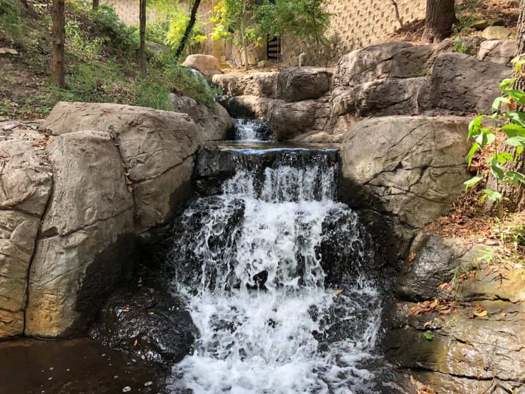 A stream with a waterfall made out of artificial rock in Arlington Texas.