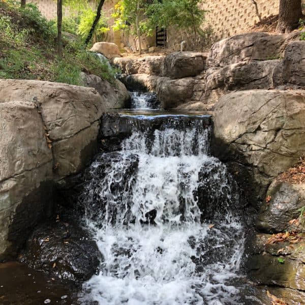 A stream with a waterfall made out of artificial rock in Arlington Texas.