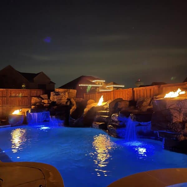 Beautiful blue pool at night lit up with fire pits